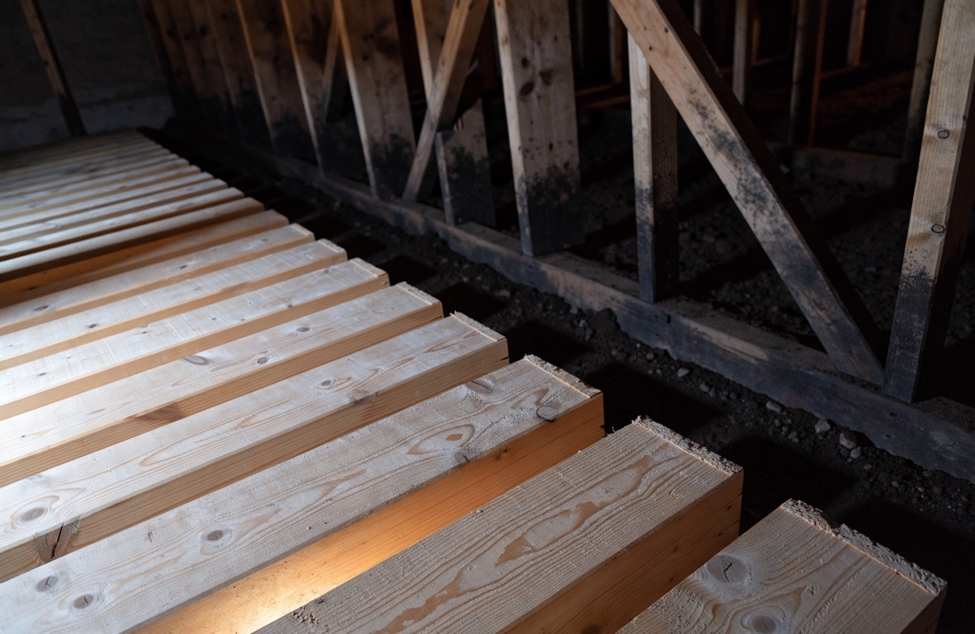 Cleaned and treated floor joists in a crawl space after remediation, with the original staining still visible on adjacent framing